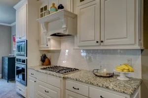 Kitchen with white cabinets, granite counters and a gas cooktop, a common spot for a wine fridge