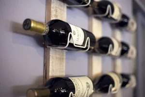 Dark wine bottles resting horizontally in a wall mounted rack with metal cradles