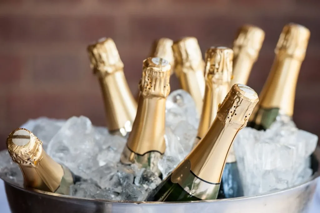 Sparkling wine bottles with gold foil necks chilling in a metal bucket of ice