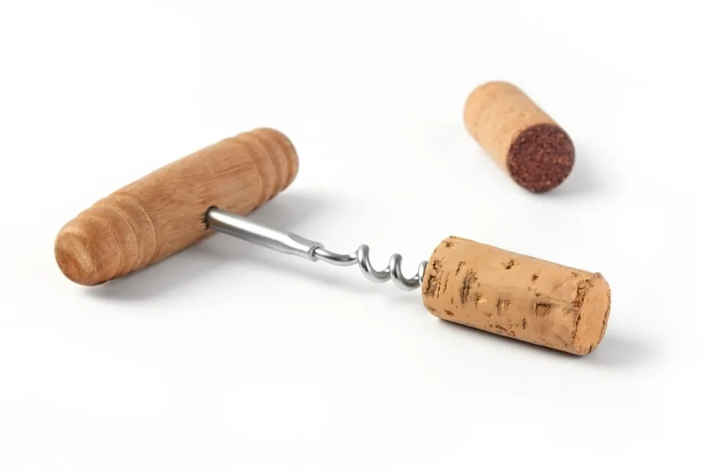 Wooden handled corkscrew holding a natural wine cork beside a second cork stained red