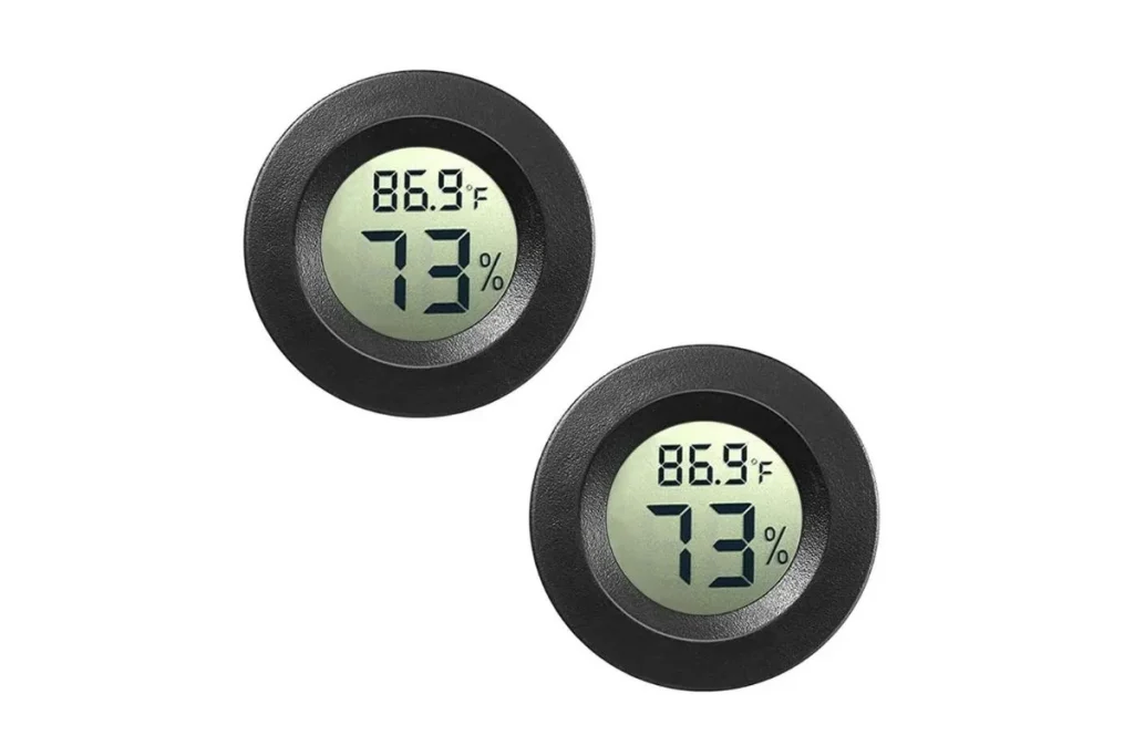 Two round black digital thermometer hygrometers showing temperature in Fahrenheit and humidity percentage