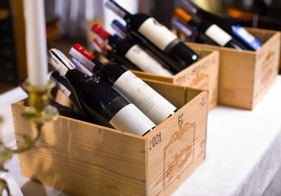 Wine bottles lying on their sides in wooden crates on a white tablecloth