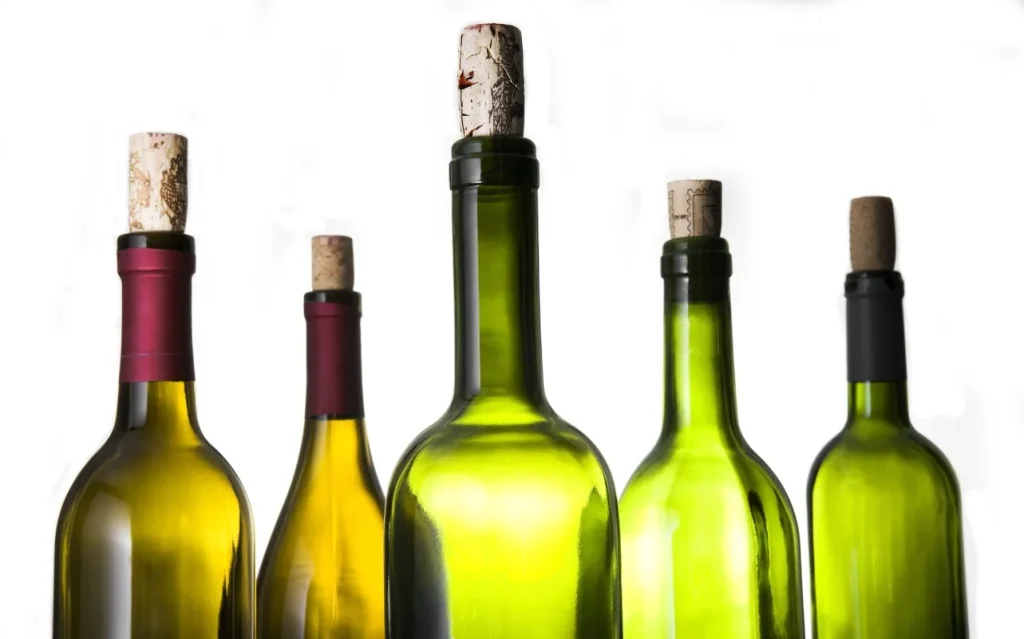 Five wine bottles in green and amber glass with corks in their necks, showing how bottle color varies