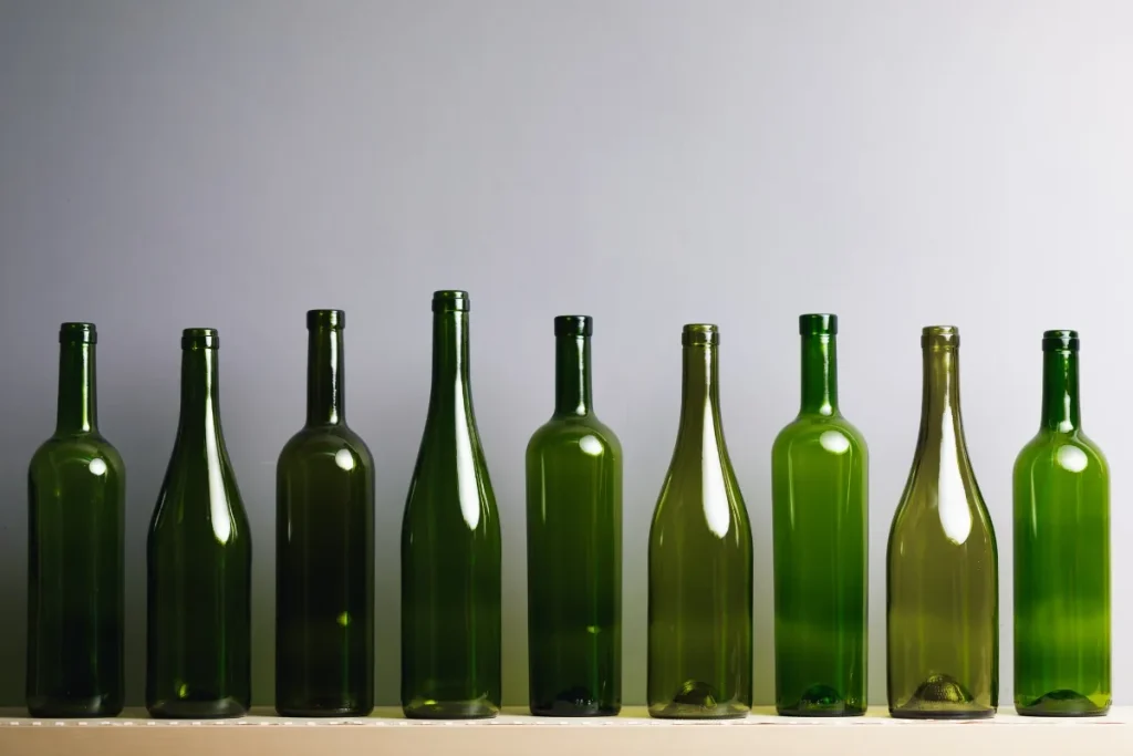 Row of empty green glass wine bottles in different shades and shapes on a shelf