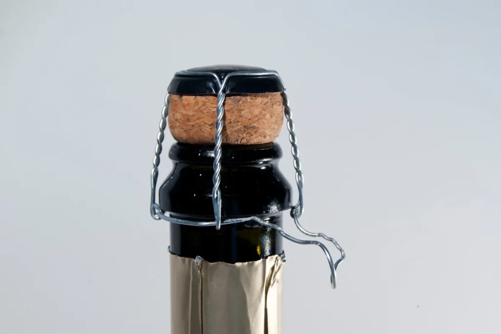 Sparkling wine bottle neck with cork, wire cage and gold foil wrapping