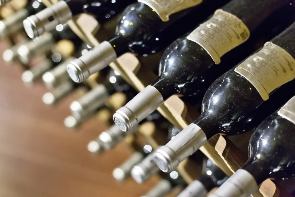 Dark wine bottles resting on their sides in a wooden cellar rack