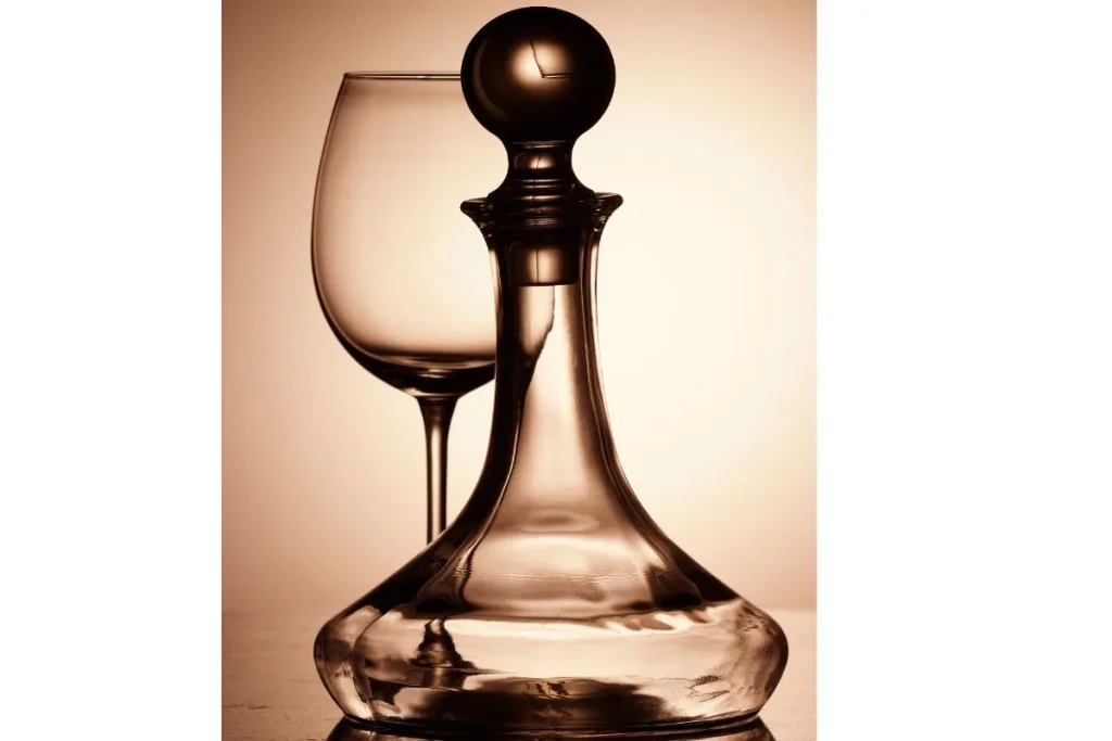 Empty glass wine decanter with a round stopper beside an empty wine glass