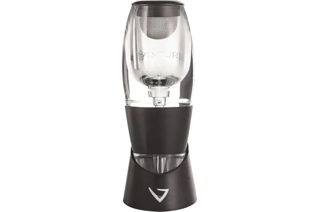 Clear handheld wine aerator with mesh filter sitting in a black base stand
