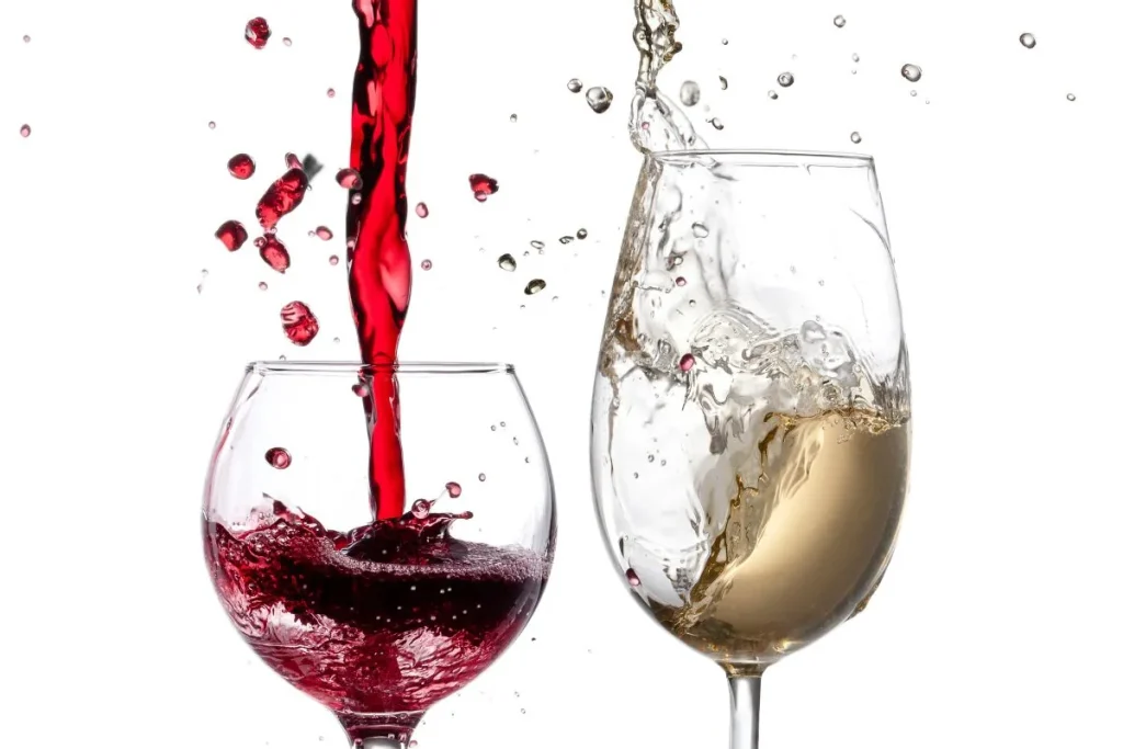 Red wine and white wine splashing into two glasses side by side