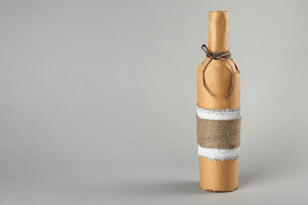 Wine bottle wrapped in brown paper with burlap bands and twine tied at the neck