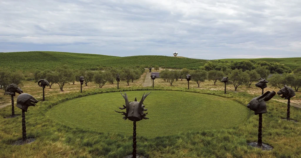 Bronze animal head sculptures ringing a grass circle with vineyard hills behind at Donum Estate
