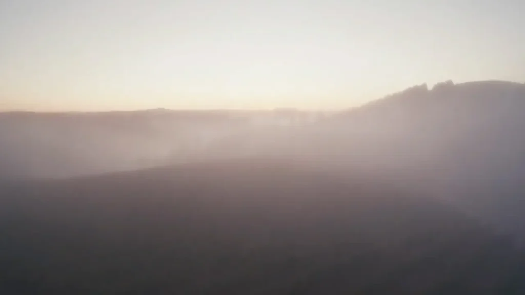 Morning fog rolling over coastal ridges and hillsides at sunrise