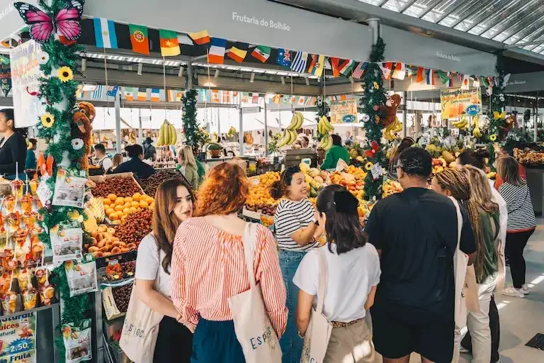 Guests browsing a colorful fruit stall inside Bolhão Market in Porto